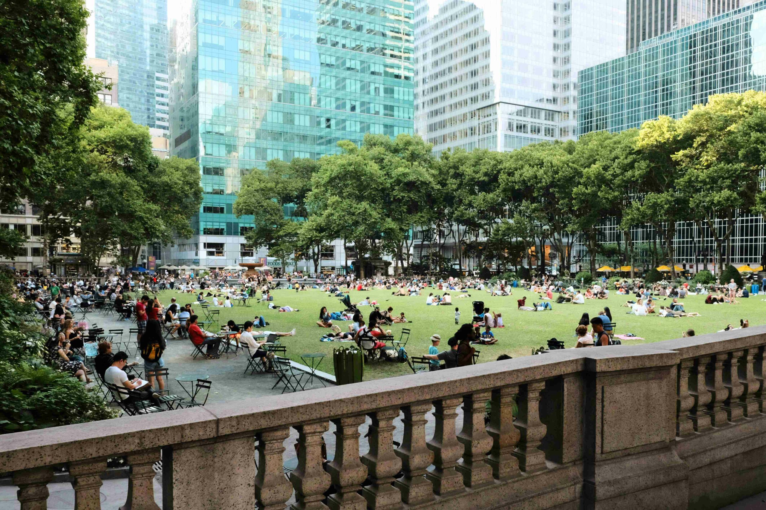 Bryant Park with many people enjoying the park in chairs and on the lawn