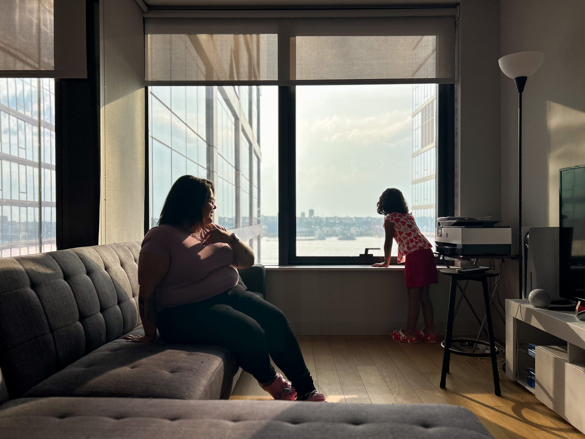 A mother and daughter in their living room with a view of the river